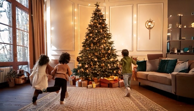 Children on Christmas morning running toward christmas tree